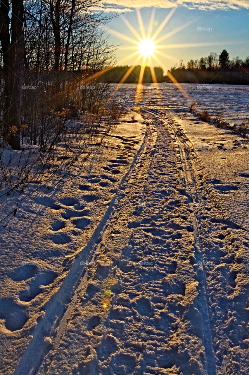sunset over snowmobile trail in winter