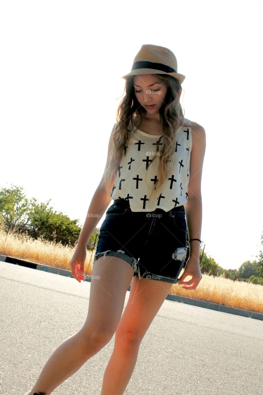 Backlit angled portrait of a pretty teenage girl looking at the pavement on a warm summer afternoon