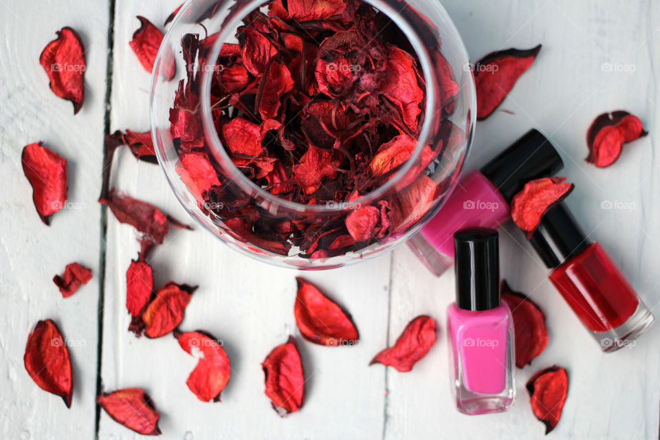 Rose flower petals with nail polish on wooden table