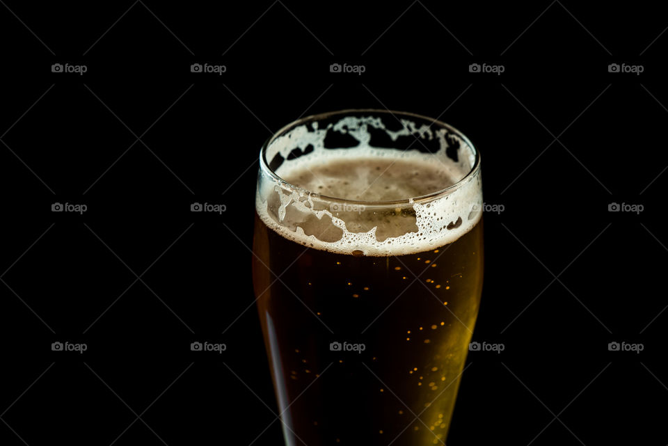 glass of golden beer isolated on black background