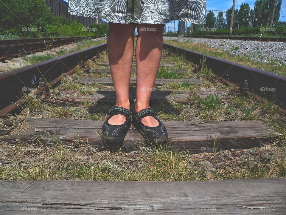 woman's feet on the railroad tracks