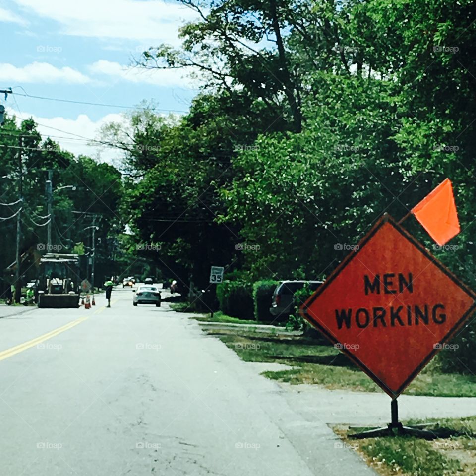 Sign on side of road warning "Men Working"