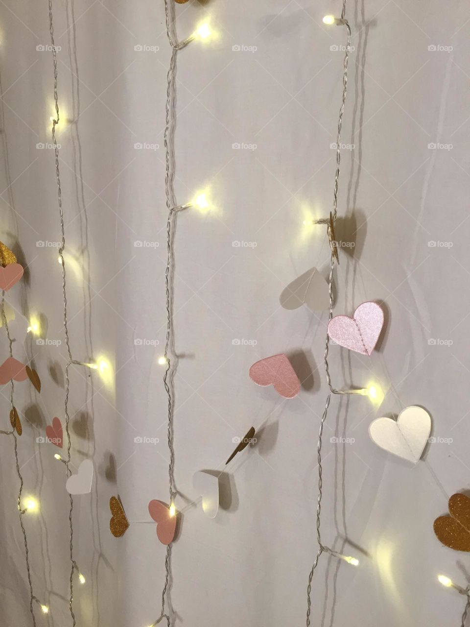 Golden hearts and lights on white curtain 
