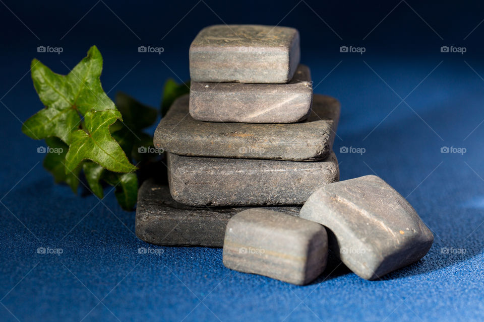 Macro photo of rectangle and square shaped slate stones with ivy on a blue background.