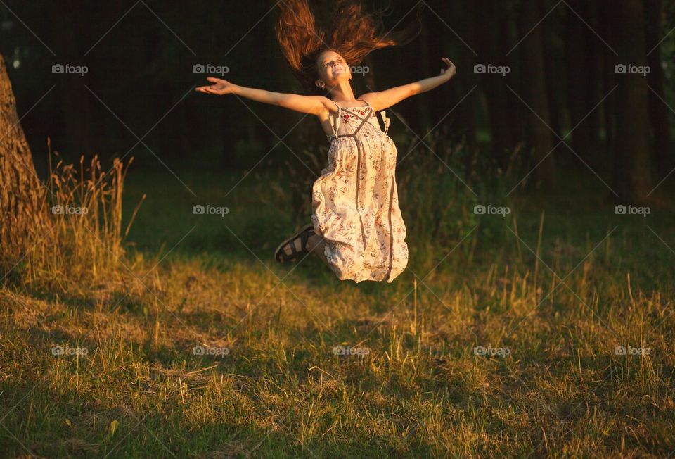 The girl jumped for joy against the background of trees in the park

￼

￼