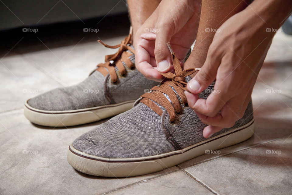 Young sportsman tying up tennis before going out to do running exercise in the morning