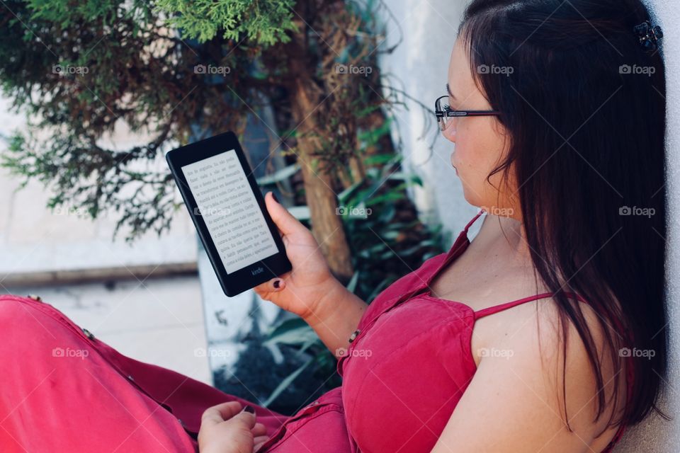 woman in red dress reading a book on Kindle