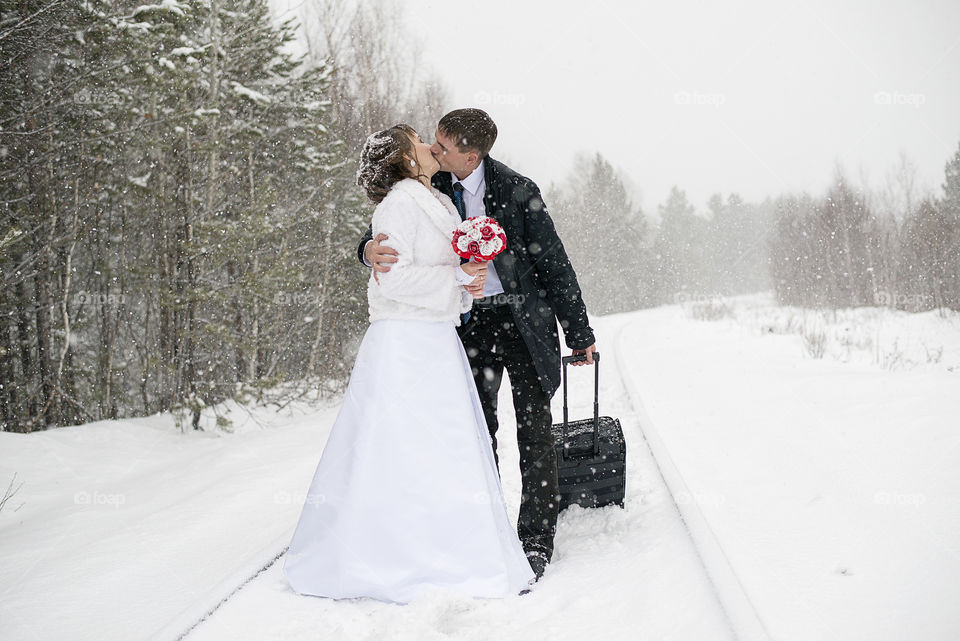 Couple kissing on snowy road in the forest