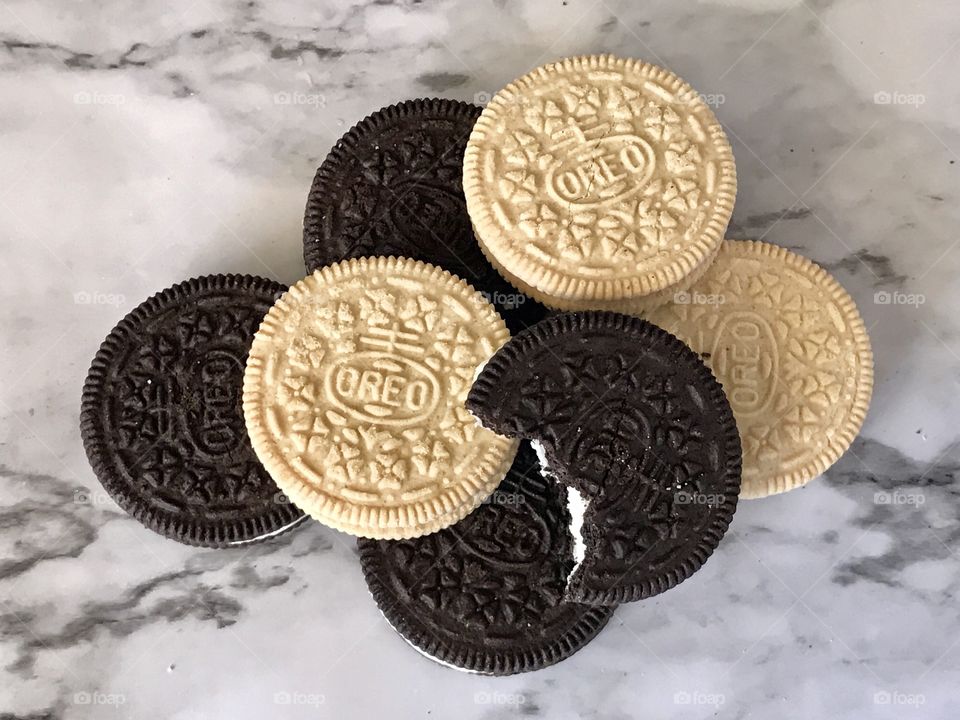 A pile of chocolate in golden double stuffed Oreo cookies with a bite taken out of the top cookie