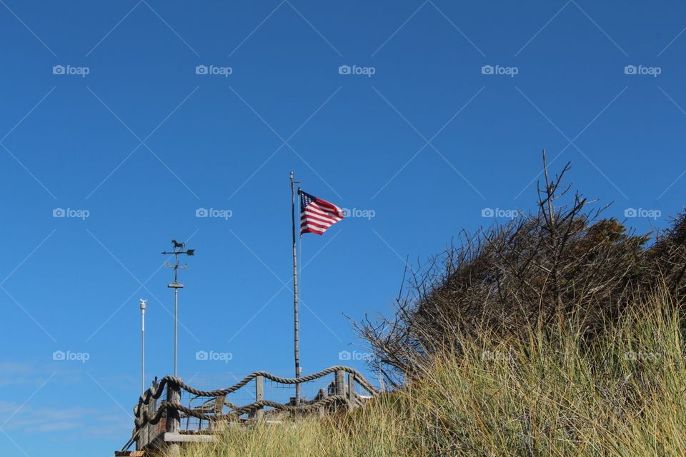 US flag on a beach grass cliff with blue sky
