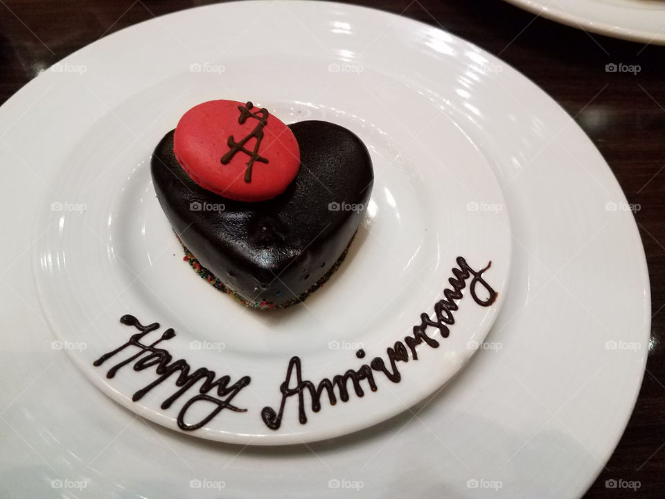 Anniversary cake with red cookie on white serving plates