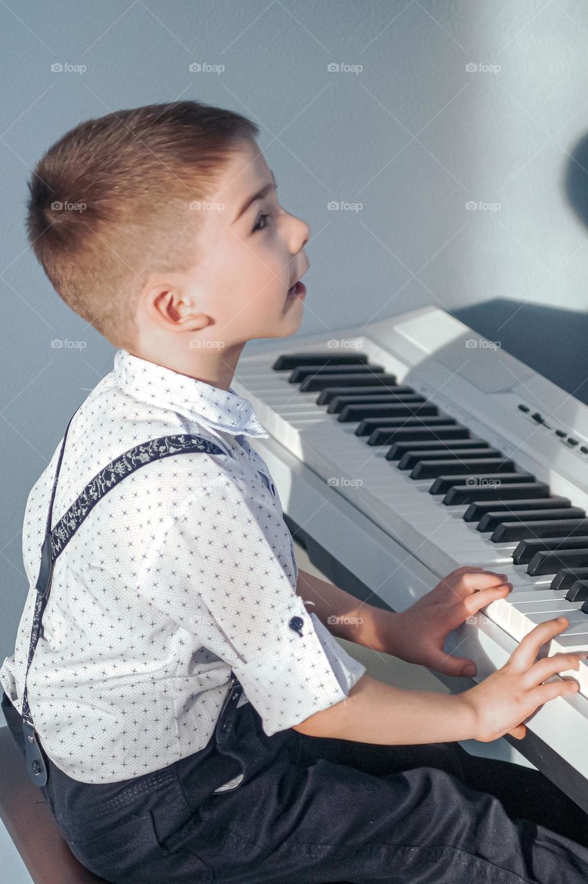 The boy sings and plays the piano