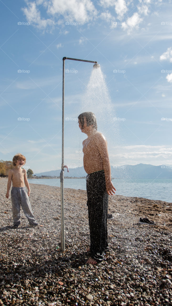 shower in autumn at the beach, two boys