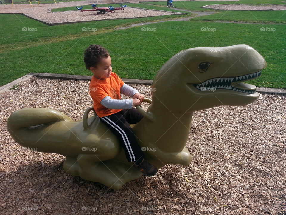 ride on dinosaur. boy riding dinosaur at playground