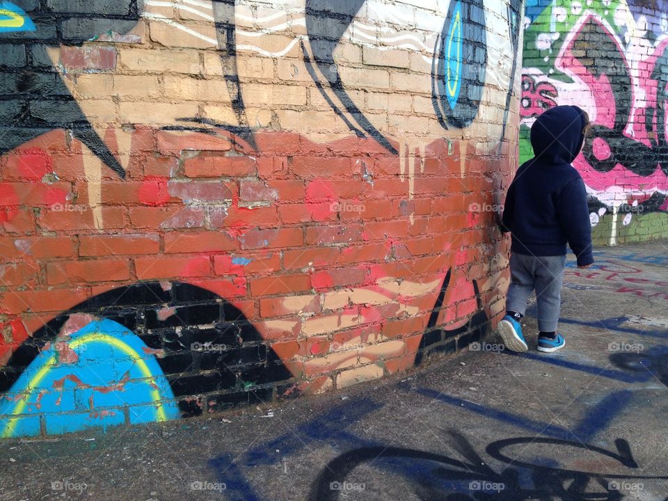 Young boy walking around looking at street art.