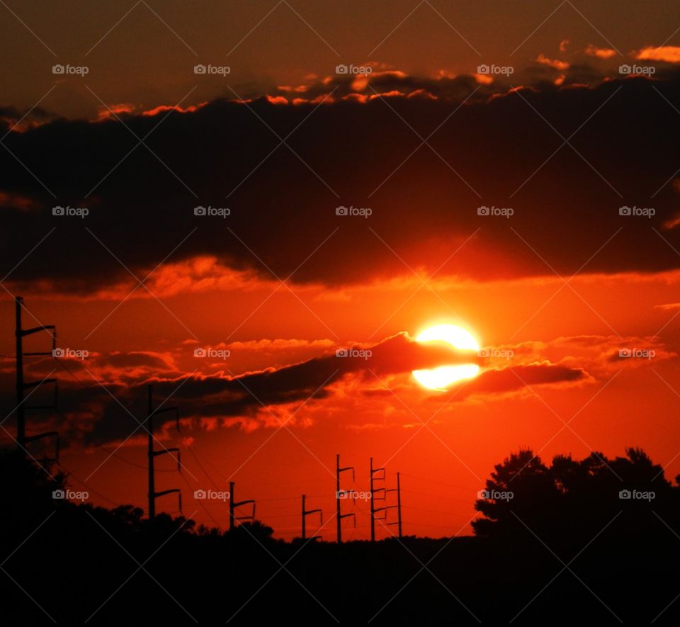 Silhouette of powerline poles against dramatic sky