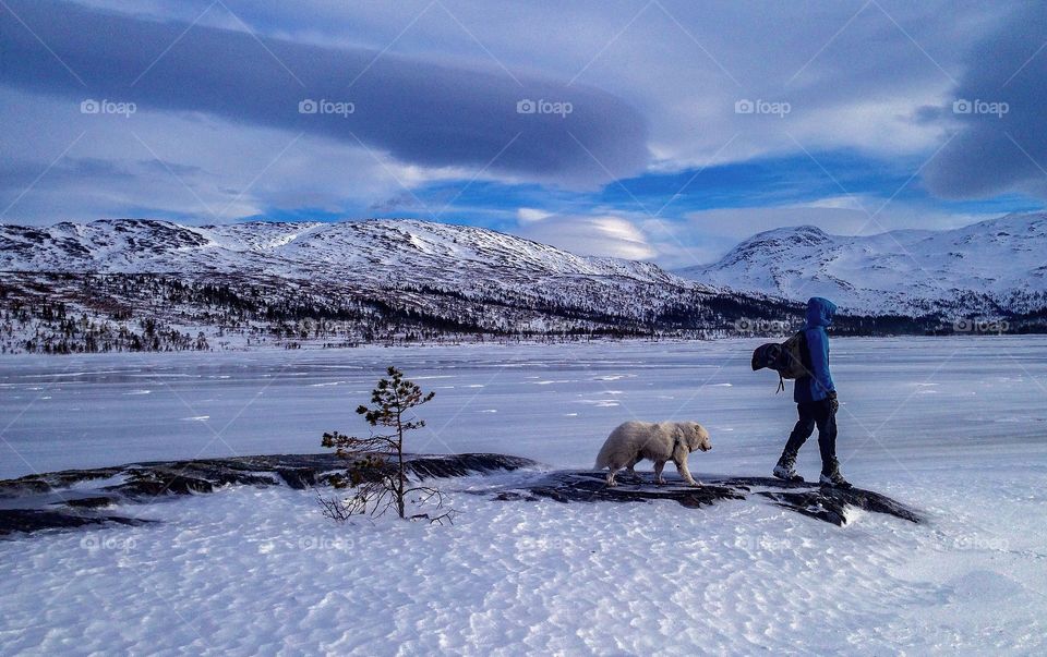 Walking the dog near a frozen lake. 
