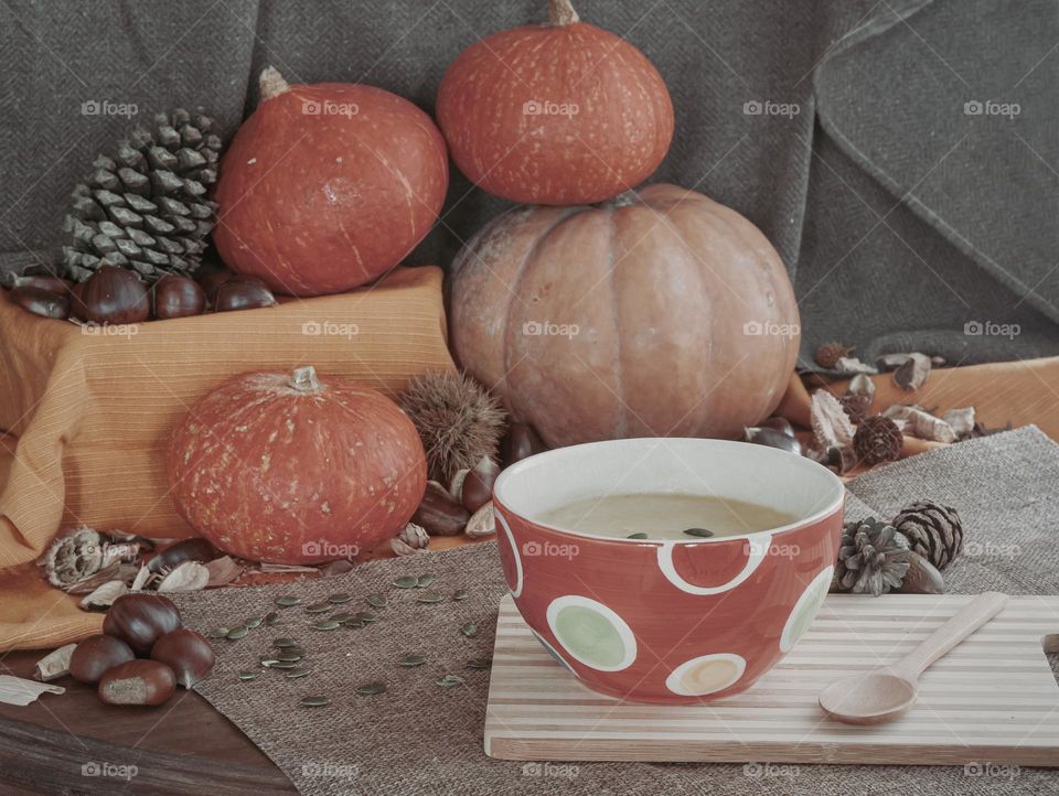 Cream of pumpkin soup served in a polka dot bowl and surrounded by autumnal fayre