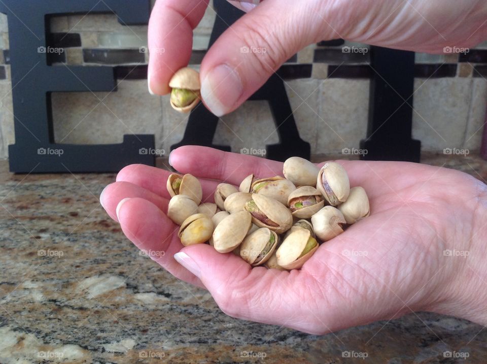 Holding a handful of pistachio nuts.