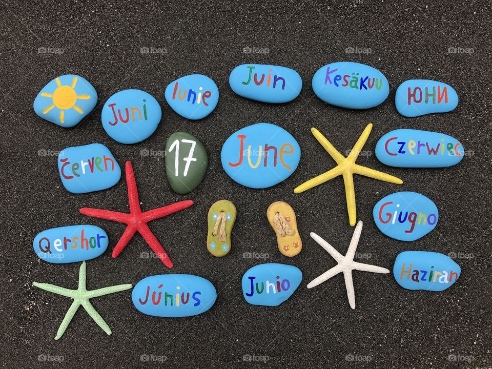 17 June, calendar date with multicolored stones and starfishes over black volcanic sand