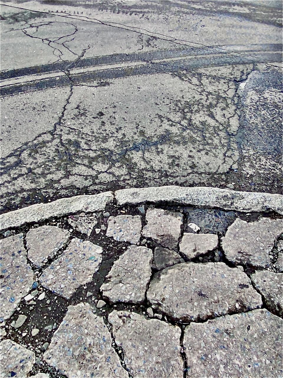 An ancient broken up pavement revealing patterns that remind of rock formations of the way they occur in nature can be found beneath the Pulaski Bridge in Long Island City, Queens by the train yard. 2021. Hypnotic Productions
