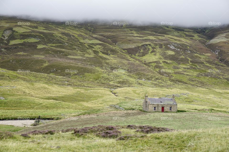 Derelict small cottage in Scotland with hill fog in the mountains above... 