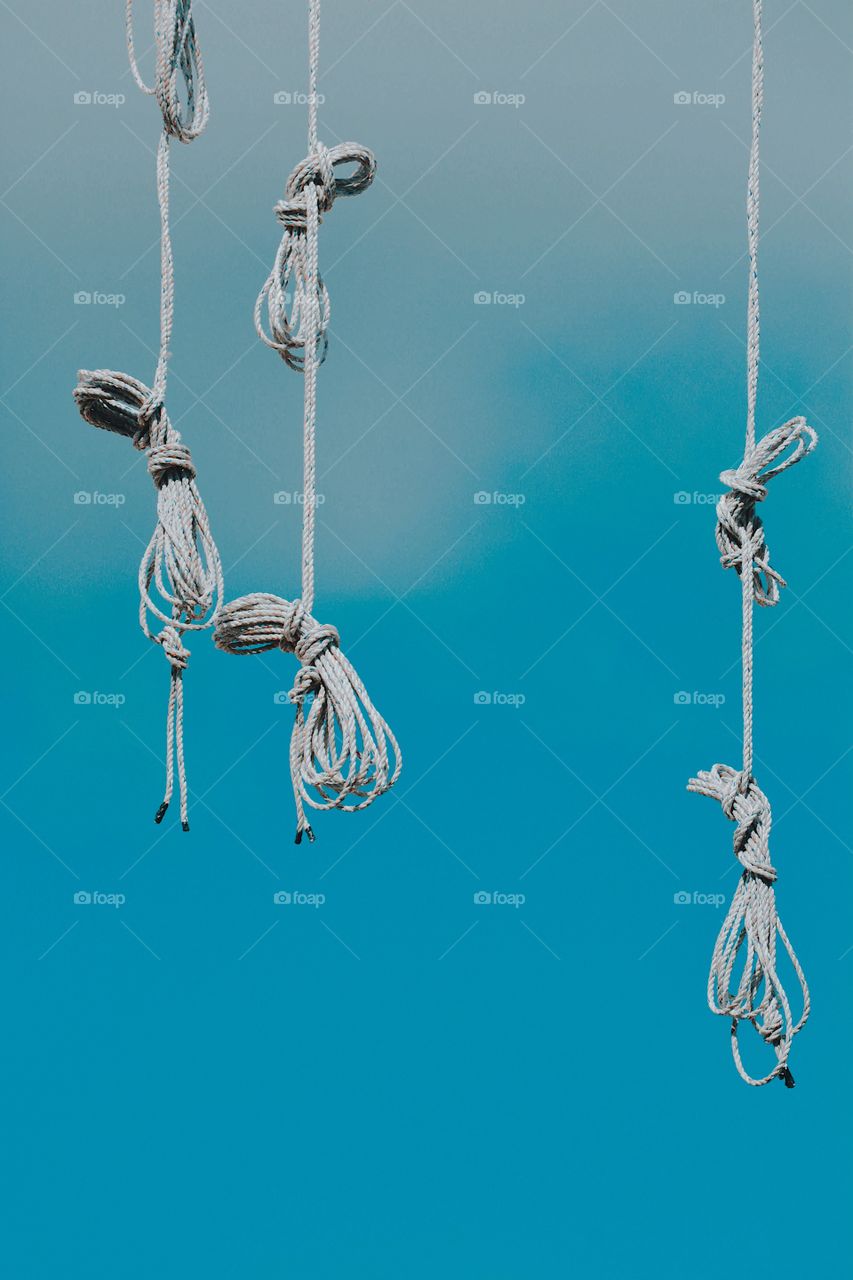 three tied wrapped up ropes hanging from the beautiful shaded blue sky. modern and aesthetic 