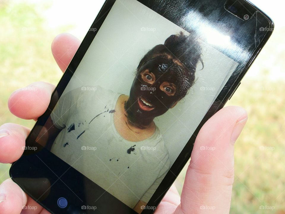 Person's hand holding mobile phone showing woman with face mask