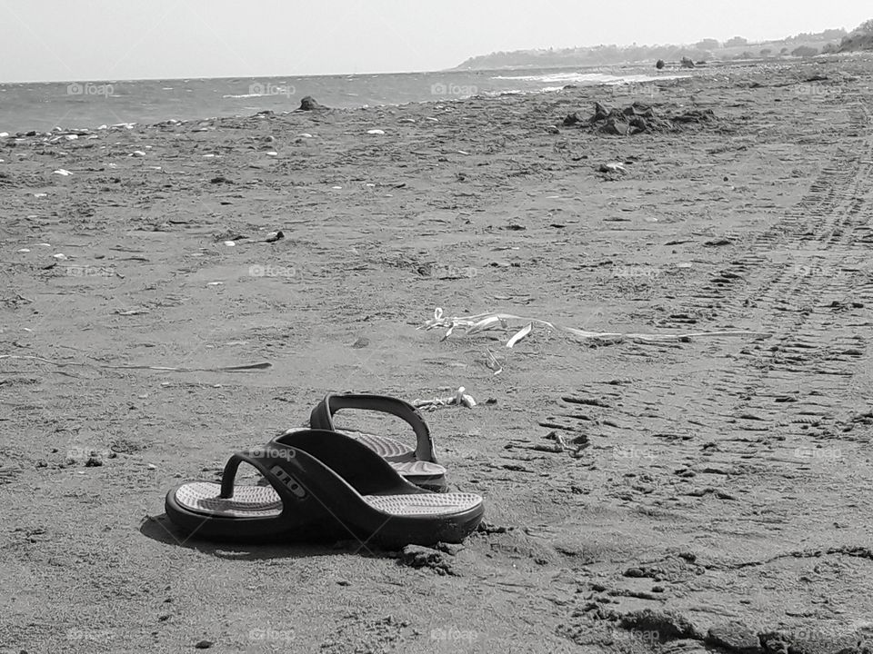 a monochrome photo with seashore and sandals