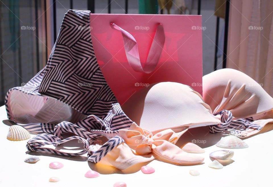 Women's swimsuit on table with seashells and decorative bag. Barbie style