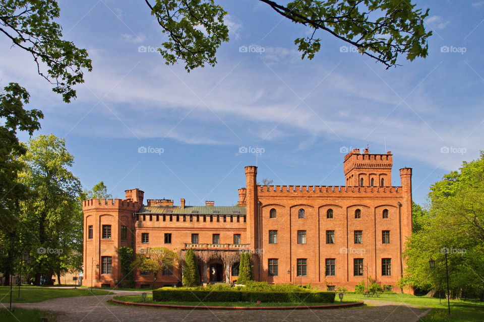 Neo-gothic castle made of orange bricks against a bright blue sky