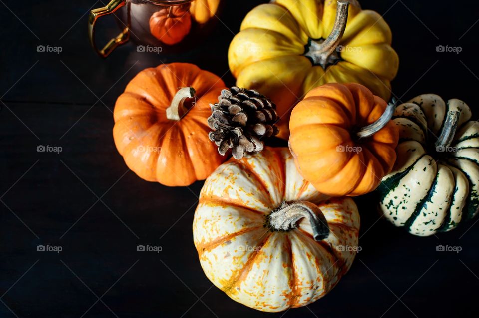 Autumnal harvest symbolic pumpkins on rustic wood table with copper mug reflection Thanksgiving Day holiday background 