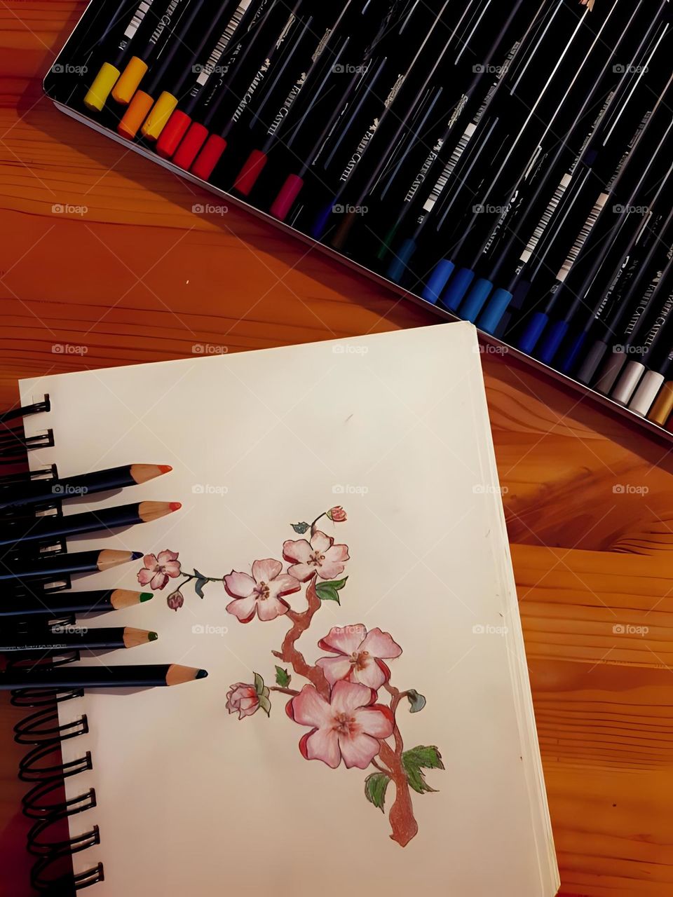 This picture represents a notebook with some pencils next to it.