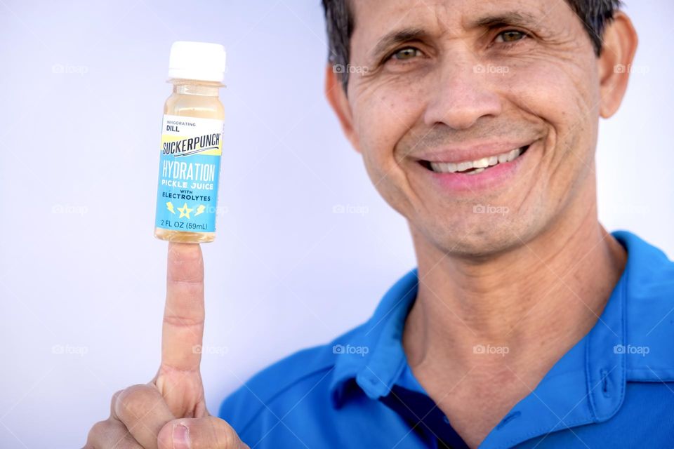 A middle-aged man of Puerto Rican decent finds a spark of energy from a shot of pickle juice. 