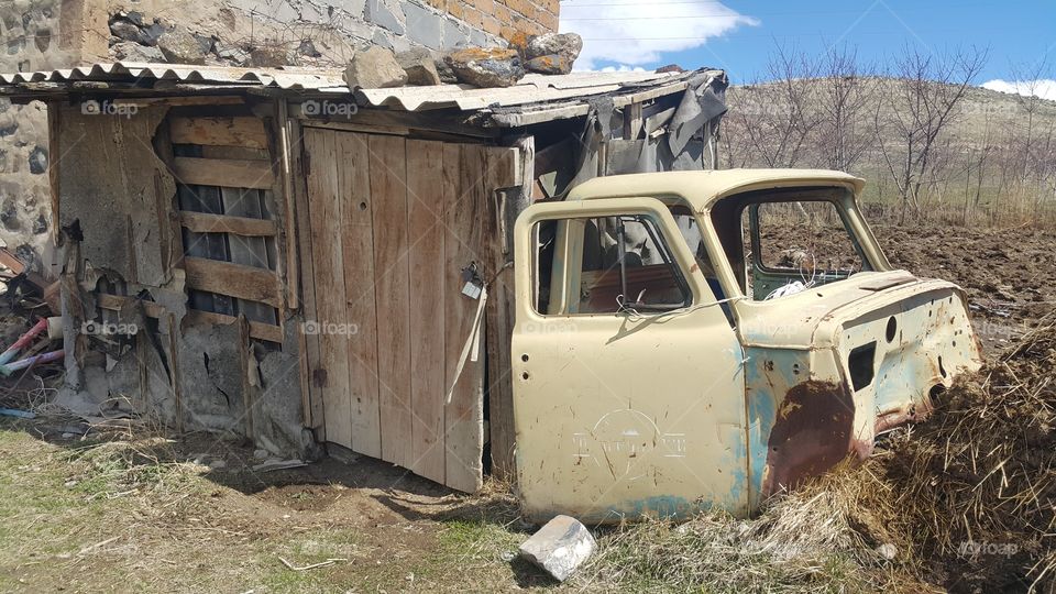 the body of an old car and the back of a small house as if it were his back
