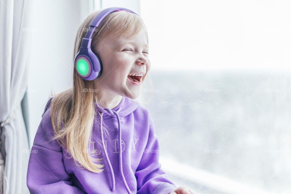 girl sitting by the window smiling and listening to music