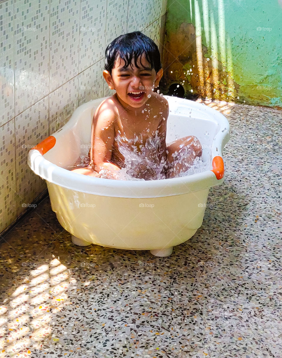 happy kid enjoying his bath in tub in summer