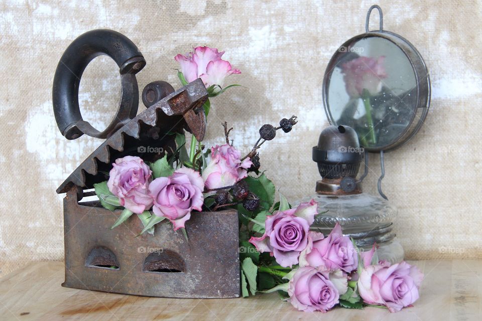 Pink roses in a iron and an old oil lamp