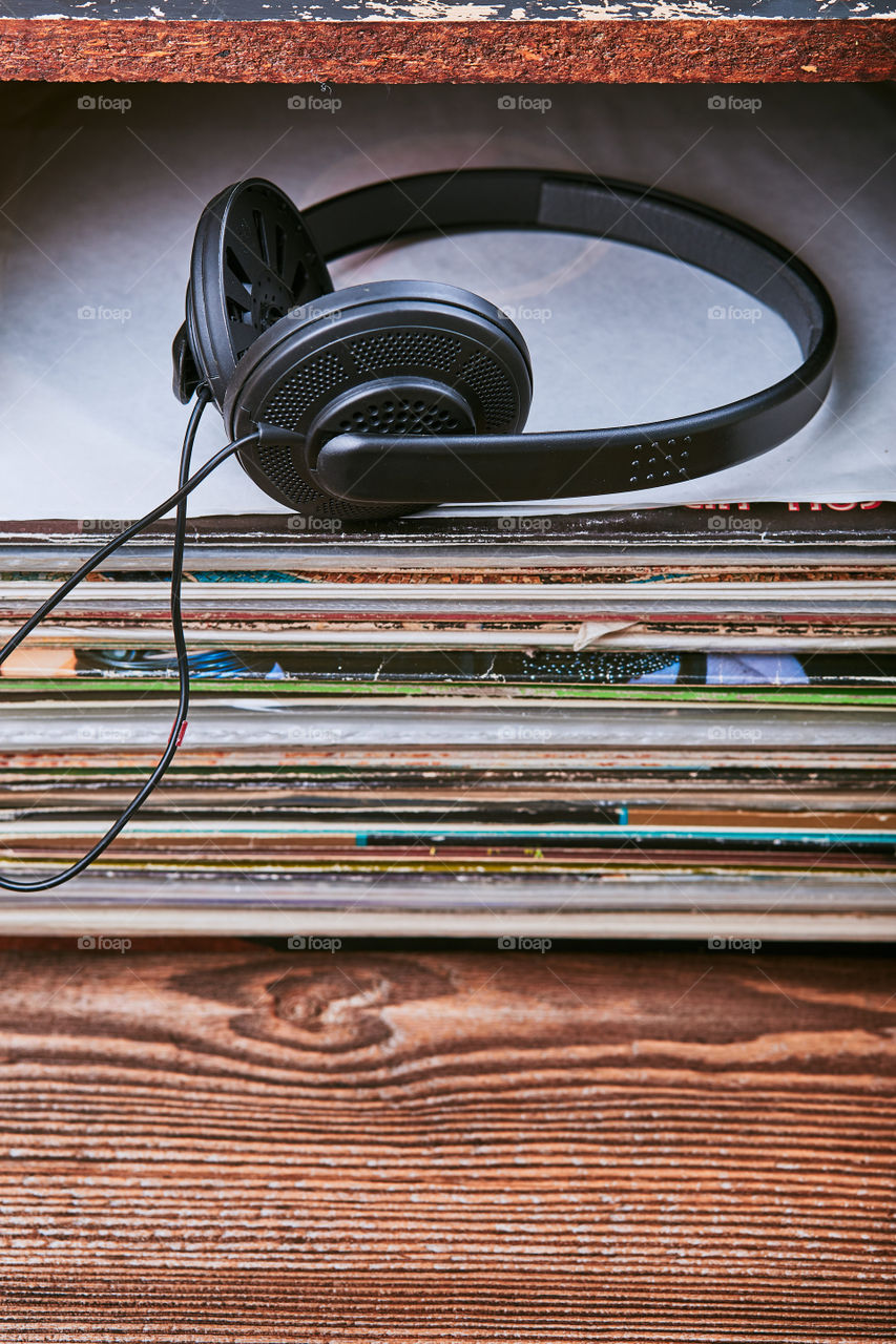 Stack of many black vinyl records and headphones put on the top of stack. Candid people, real moments, authentic situations