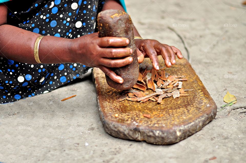 Woman brake the cinnamon spices with stone