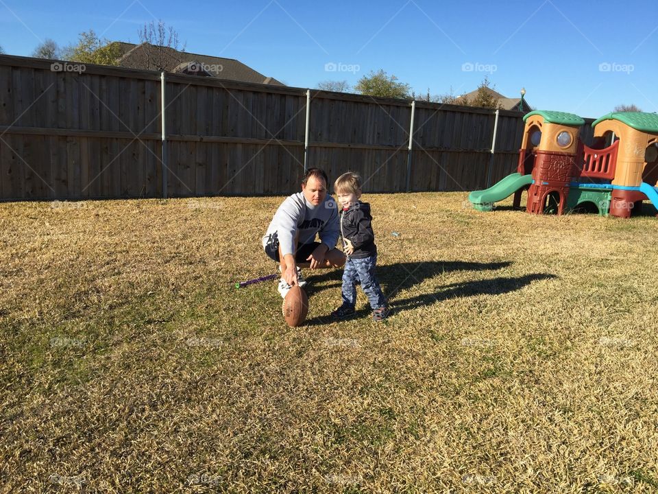 Dad teaching his son to kick a football 