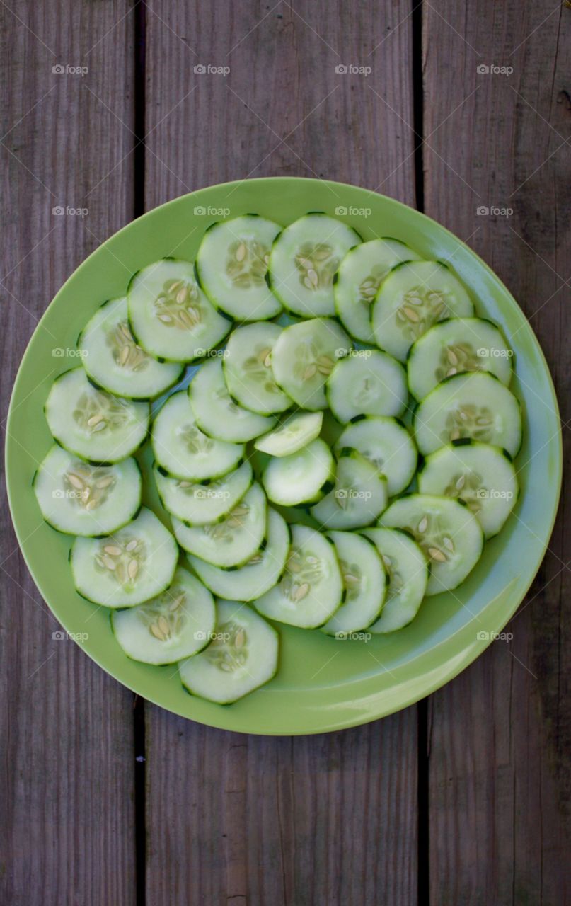 Fruits! - Cucumbers in a spiral pattern on a green plate on a wooden background