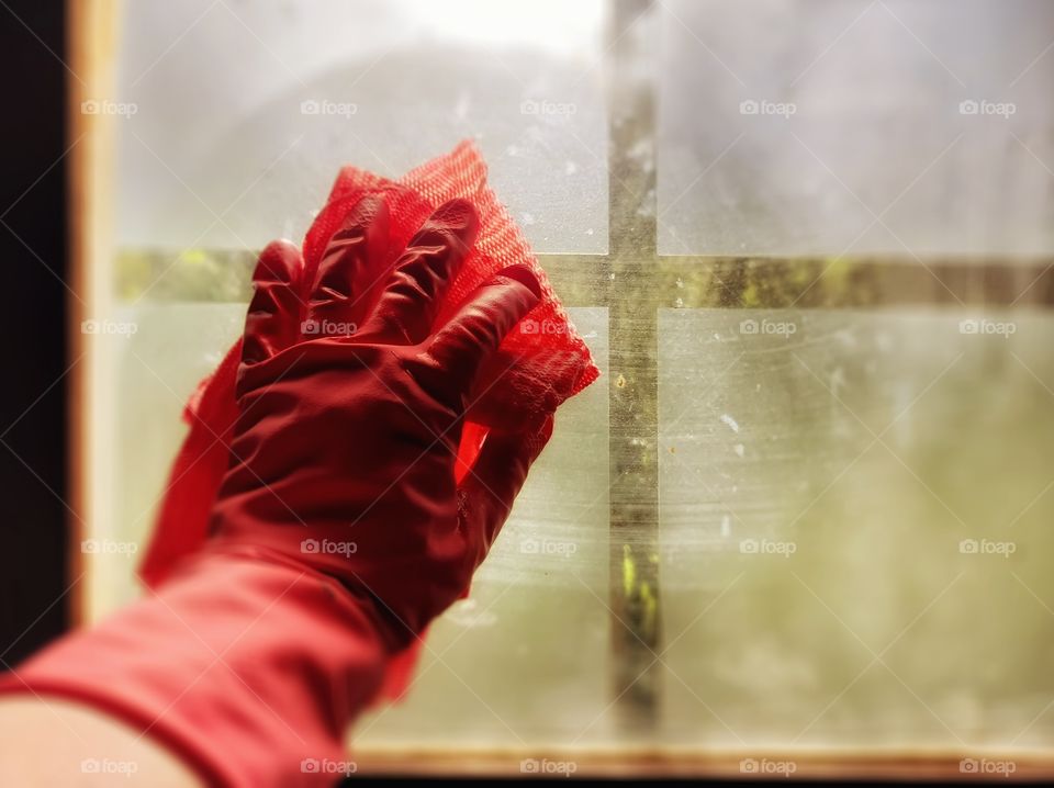 Cleaning the window with red rubber glove