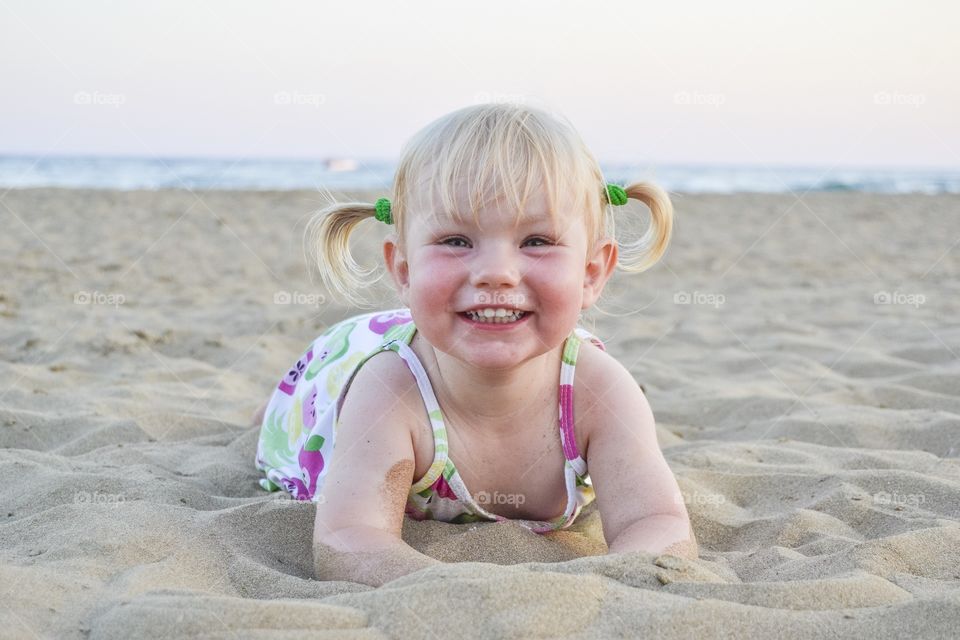 Two year old happy girl playing in on the beach in Turkey on their holiday.