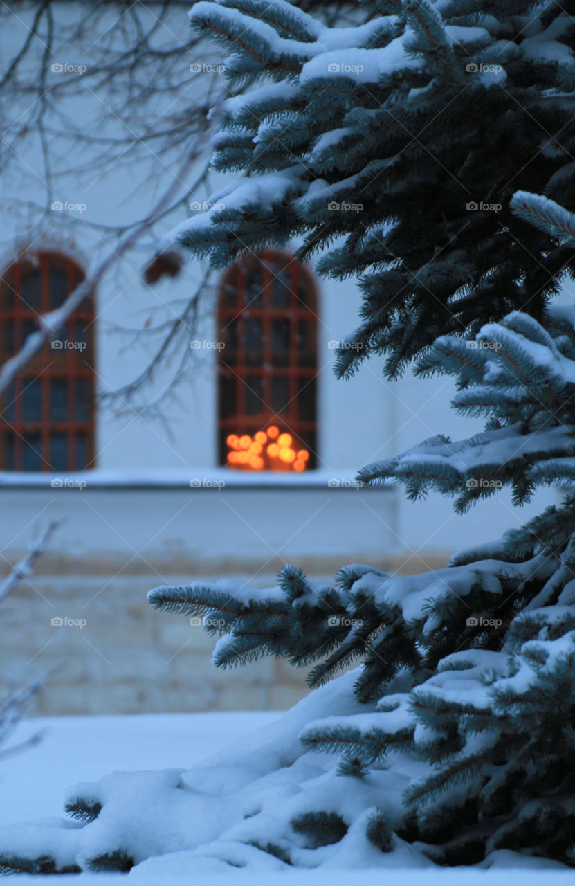 Candlelight in the window.  Church.  Christmas.  Winter fairy tale.  Snow-covered Christmas tree at the church.