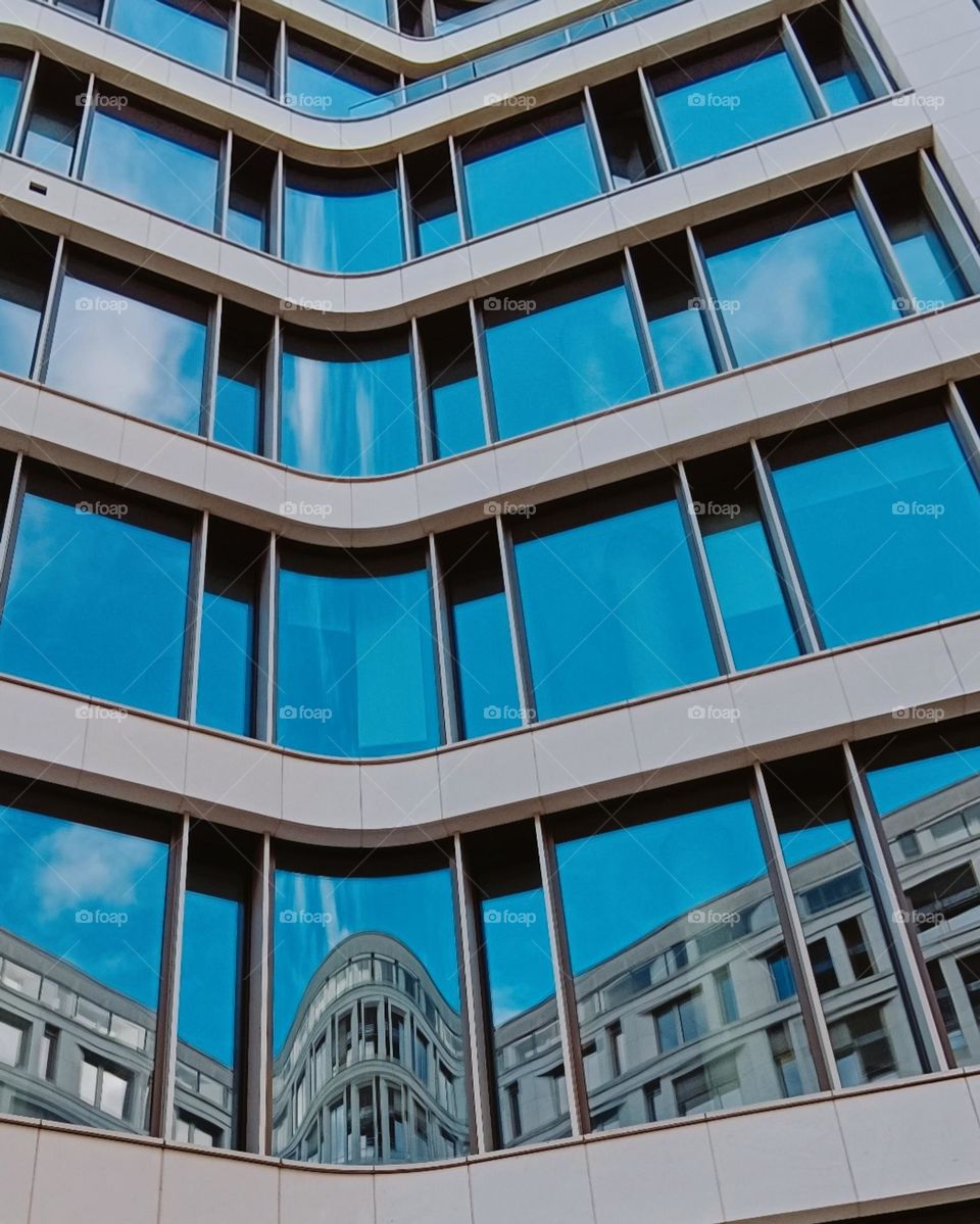 Glazed front of a building with reflection of blue sky an an other building