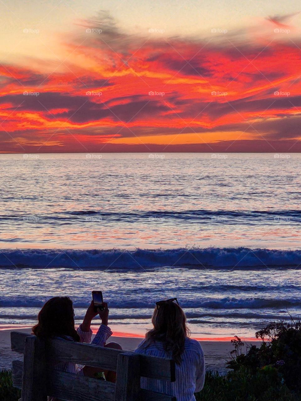 Young ladies enjoy a awesome sunset in San Diego and make sure to record it with their cellphone