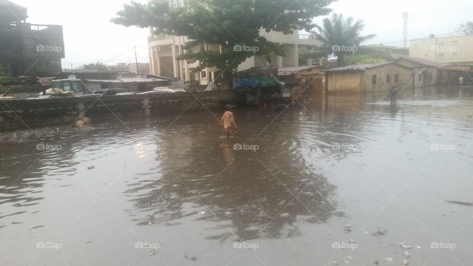 The image of a child's feet in the water, after the flood of a street of Cotonou after a rain of 10 minutes