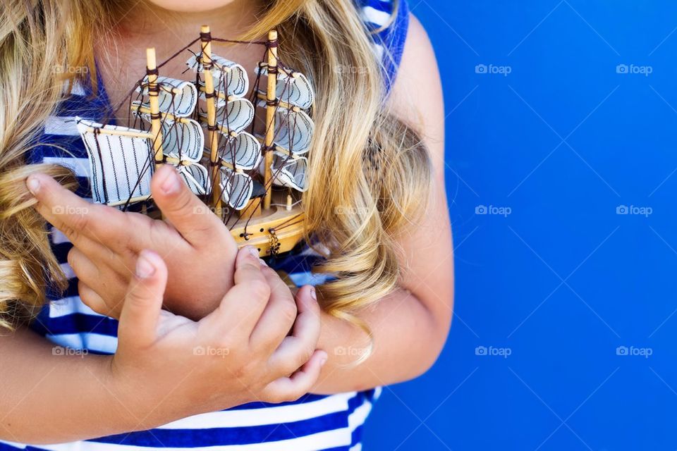 Mid section of girl holding toy boat