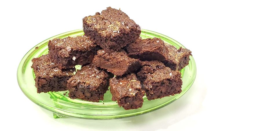 Chocolate brownies on a green glass plate with a white background 